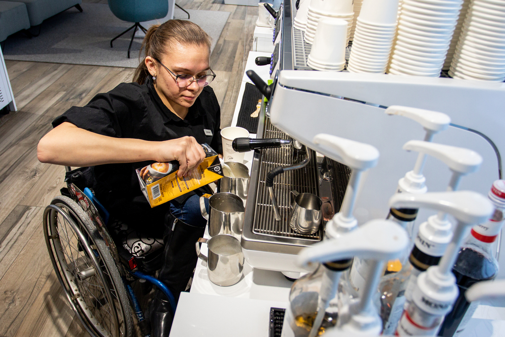 Wheelchair disabled person works as a barista in an inclusive coffee shop.